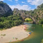 Vibrant scene of kayakers at the iconic Pont d'Arc in Ardèche Gorge, France.