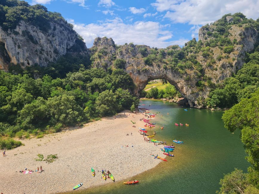 Vibrant scene of kayakers at the iconic Pont d'Arc in Ardèche Gorge, France.