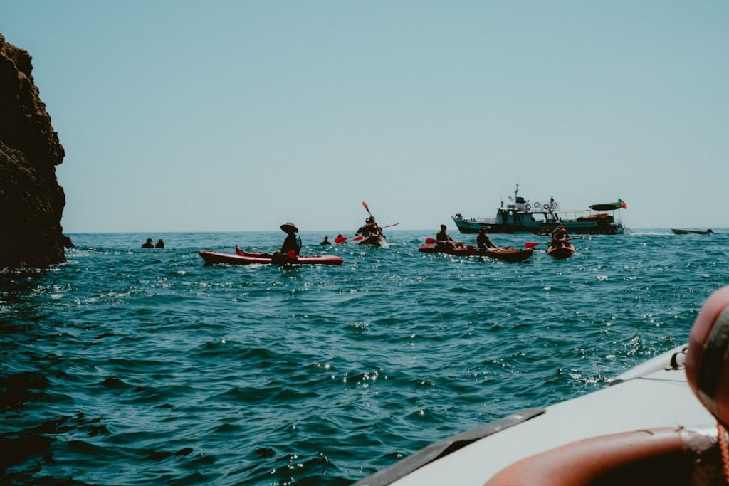 Kayakers paddle on the ocean near a boat.