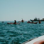 Kayakers paddle on the ocean near a boat.