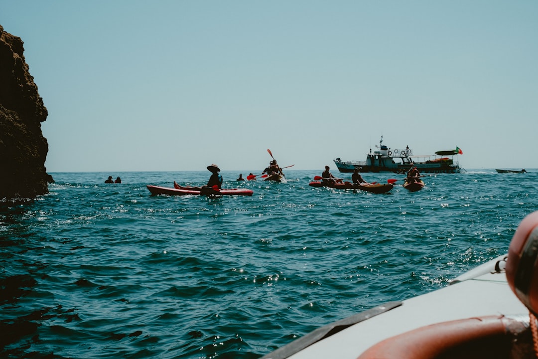 Kayakers paddle on the ocean near a boat.
