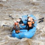 Exciting white water rafting experience with group navigating rapids in inflatable raft.