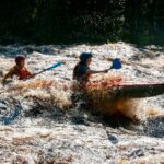 a group of people paddle a canoe down a river