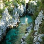 A breathtaking view of a turquoise river winding through a rocky canyon in Bovec, Slovenia.
